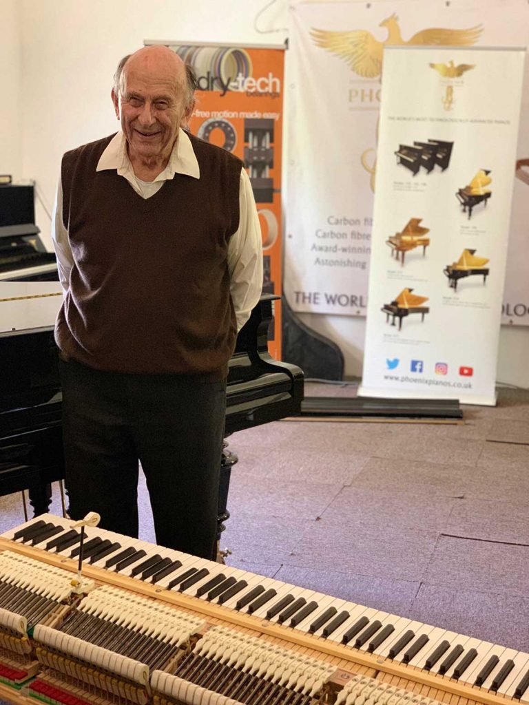 Engineer Richard Dain posing with a piano that utilizes his 3D printed hammer design